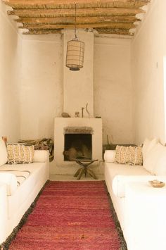 a living room filled with white couches and a red rug on the floor next to a fire place