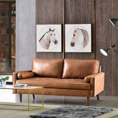 a brown leather couch sitting in a living room next to a glass table and lamp