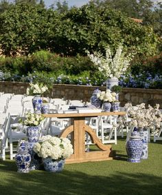 an outdoor wedding setup with blue and white vases on the grass, chairs in the background