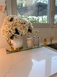 a white counter top sitting under a window next to a sink and faucet