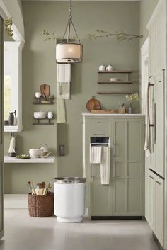 a kitchen with green walls and white cabinets in the center, along with an open storage area