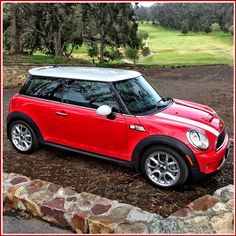 a red mini cooper parked in front of some trees