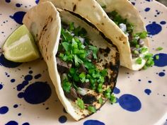 two tacos on a plate with green onions and cilantro garnish