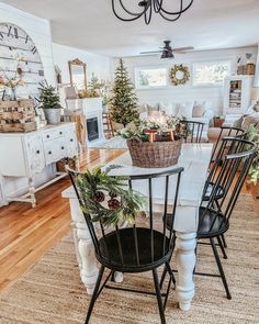 the dining room table is decorated with greenery and christmas wreaths, while the living room has a fireplace in the background