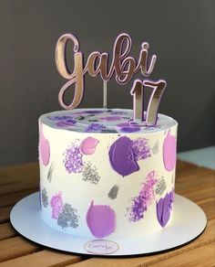 a white cake with pink and purple decorations on it that says gabii 17