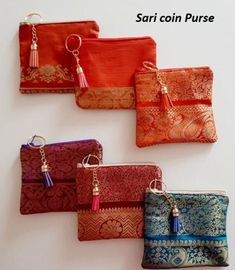 four different purses with tassels hanging from the side on a white wall