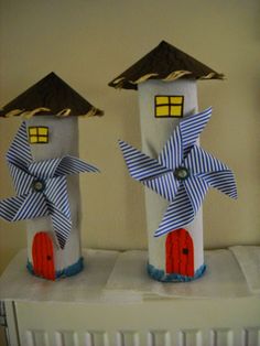 two little houses made out of toilet paper with bows on the roof and windows painted blue