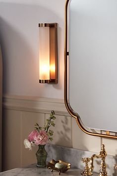 a bathroom sink with a mirror above it and flowers in a vase on the counter