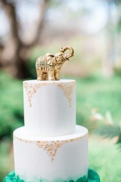 a white and gold wedding cake with an elephant on top