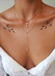 a woman with tattoos on her chest wearing a cross and arrow choker necklace in gold