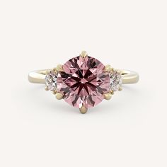 a pink diamond ring with three diamonds on the band and an oval shaped center stone