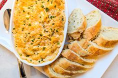 a white plate topped with bread next to a bowl of dip and slices of bread