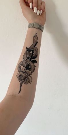 a woman's arm with a snake tattoo on it, and a ring around the wrist