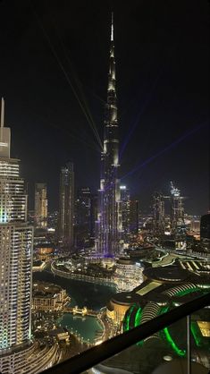 the city skyline is lit up at night, with skyscrapers in the foreground