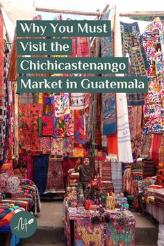 an outdoor market with lots of colorful fabrics and rugs on display in front of it