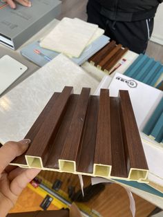 a person is holding up some brown and white wood planks in front of them