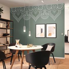 a dining room with green walls and black chairs in front of a white table surrounded by bookshelves