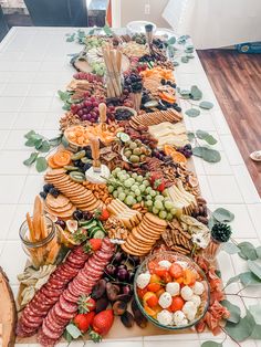 a long table filled with lots of different types of food on top of white tiles