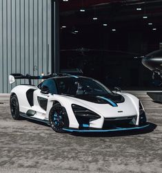 a white and blue sports car parked in front of a hangar