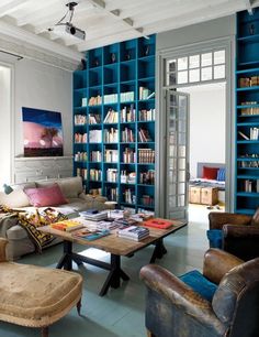 a living room filled with lots of furniture and bookshelves covered in blue bookcases