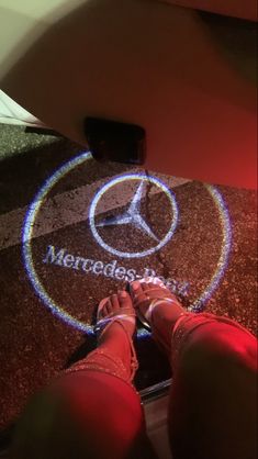 someone standing on the floor with their feet up in front of a mercedes car logo