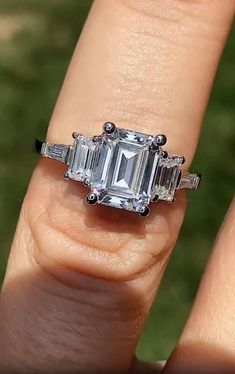 a woman's engagement ring with an emerald cut diamond