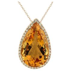 Impressive pendant featuring a very large citrine, approx. 27.46 carats, cut in a pear shape with facets. The gemstone exhibits a deep, intense orange-yellow hue, commonly referred to as Palmyra Citrine. The voluminous gemstone is meticulously cut, allowing for a subtle gradient in brightness from the tip to the base, showcasing shades from golden brown to sunny orange. Surrounding the citrine are brilliant-cut diamonds, approx. 0.51 carats in total. Color: G, and Clarity: VS. A high undergallery ensures that the citrine has ample space, preventing the lower part from resting on the décolleté during wear. Despite its size, the drop pendant maintains an airy feel due to its zigzag linear lattice. The pendant is securely attached to a 1.3 mm diameter anchor chain, fastened with a lobster cla Luxury Orange Citrine Necklace, Anchor Chain, Color Naranja, Colored Gems, Drop Pendant, Golden Brown, Pear Shape, Brilliant Cut Diamond, Orange Yellow