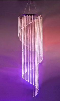 a chandelier hanging from the ceiling with purple lights on it's sides