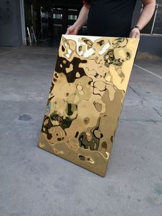 a man is holding a large piece of art that looks like it has gold paint on it