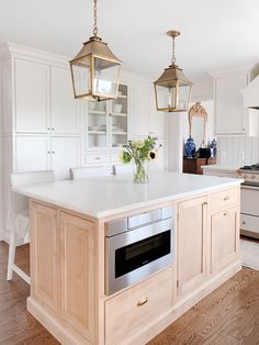 a kitchen with an island and two hanging lights over it's stove top oven