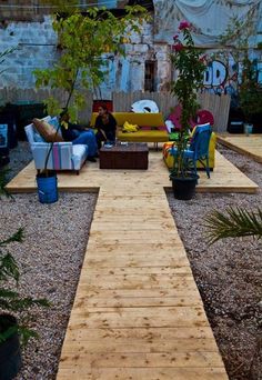 an image of a wooden walkway in the middle of a yard with furniture on it