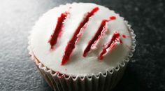 a cupcake with white frosting and red sprinkles sitting on a table