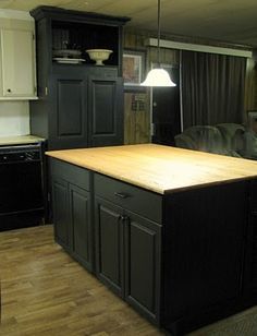 a kitchen with an island in the middle of it and black cabinets on either side