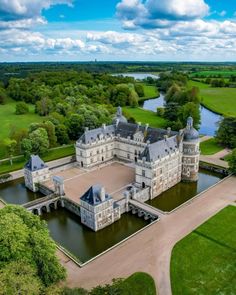 an aerial view of a large castle in the middle of a green field with water