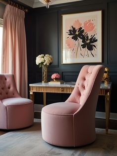 a pink chair sitting in front of a desk next to a painting on the wall