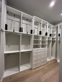 an empty walk in closet with white shelves and drawers