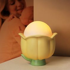 a yellow lamp sitting on top of a table next to a baby's head