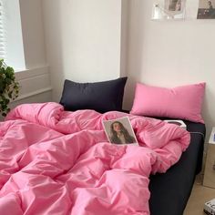 an unmade bed with pink sheets and pillows on top of it in a bedroom