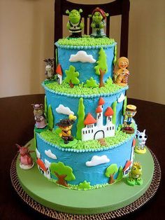 a three tiered cake decorated with cartoon characters on it's sides and green icing