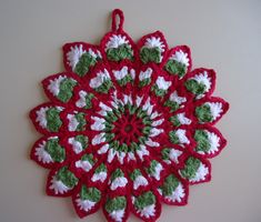 a red and white crocheted doily with green leaves on it's center