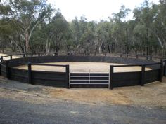 a black and white horse pen with trees in the background