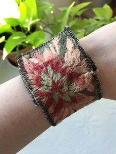 a close up of a person's arm wearing a bracelet with flowers on it