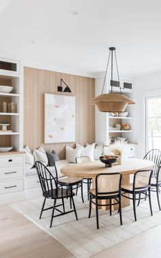 the dining room table is surrounded by black chairs and white walls with open shelving