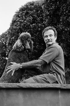 a black and white photo of a man holding a dog