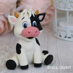 a small toy cow sitting on top of a table next to pink roses and other decorations