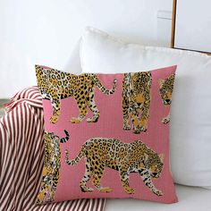 a pink pillow with leopards on it next to a red and white striped pillow