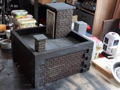 a small brick oven sitting on top of a wooden table next to a pile of boxes