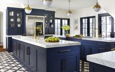 a large kitchen with blue cabinets and white counter tops, black and white checkered flooring