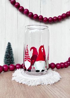 a glass with some red and white designs on it sitting next to a christmas tree