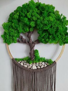 a green tree is in the middle of a wall hanging with white rocks and grass